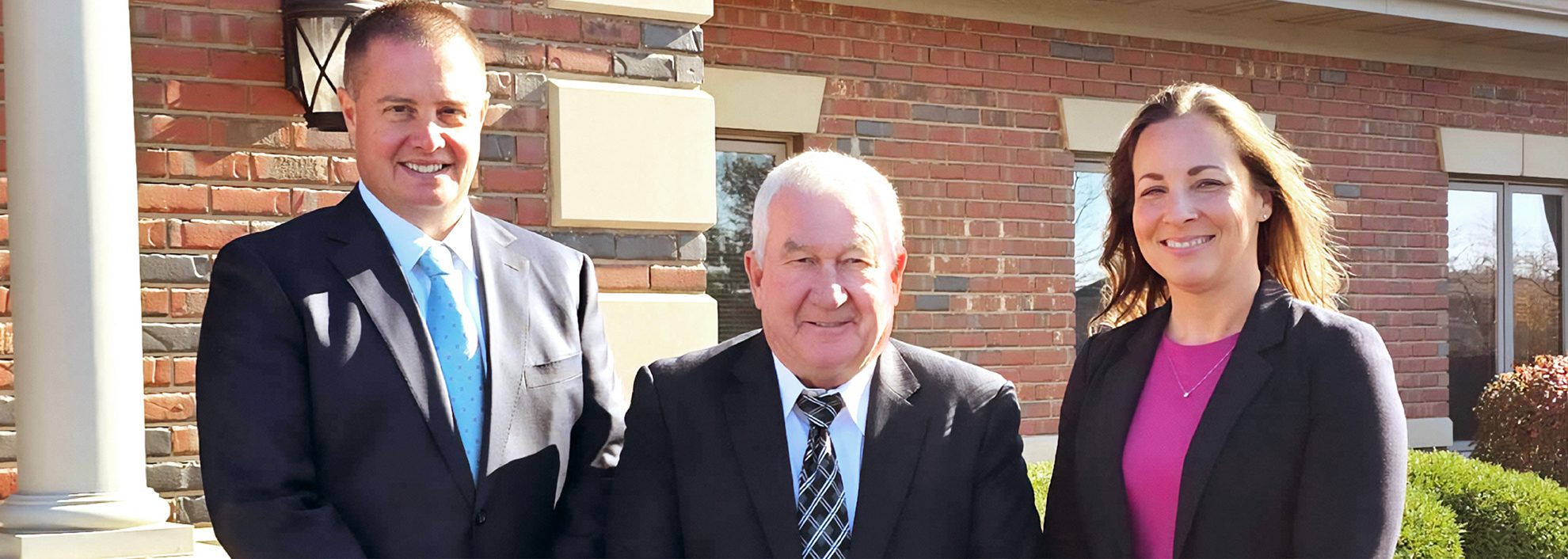 Shawn Sabau, Randall Minas, and Elisha Porterfield in front of branch office building